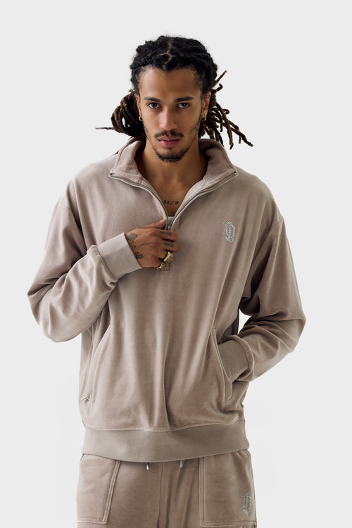 Model wearing Fungi velour half‑zip track jacket partially unzipped with funnel collar; jacket features diamanté ''DL'' monogram on chest, side pockets, ribbed cuffs and hem and matching pants.