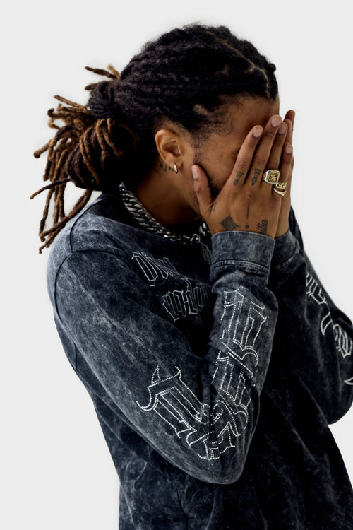Front view of the black acid‑wash long‑sleeve T‑shirt on a model with printed 'Dirty London' script across upper right chest and diamanté ''DL'' monogram lettering down the sleeve.